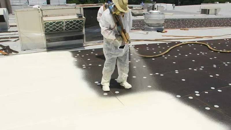 Crew applying spray foam roofing to a flat commercial roof